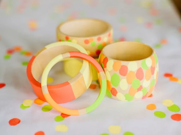 neon colored stripes, ad paint daubs, decorating five wooden bangles, with different shapes