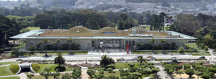 postmodern buildings, grassy area with small artificial hills, on the roof of a large, but not very tall building, surrounded by gardens and trees