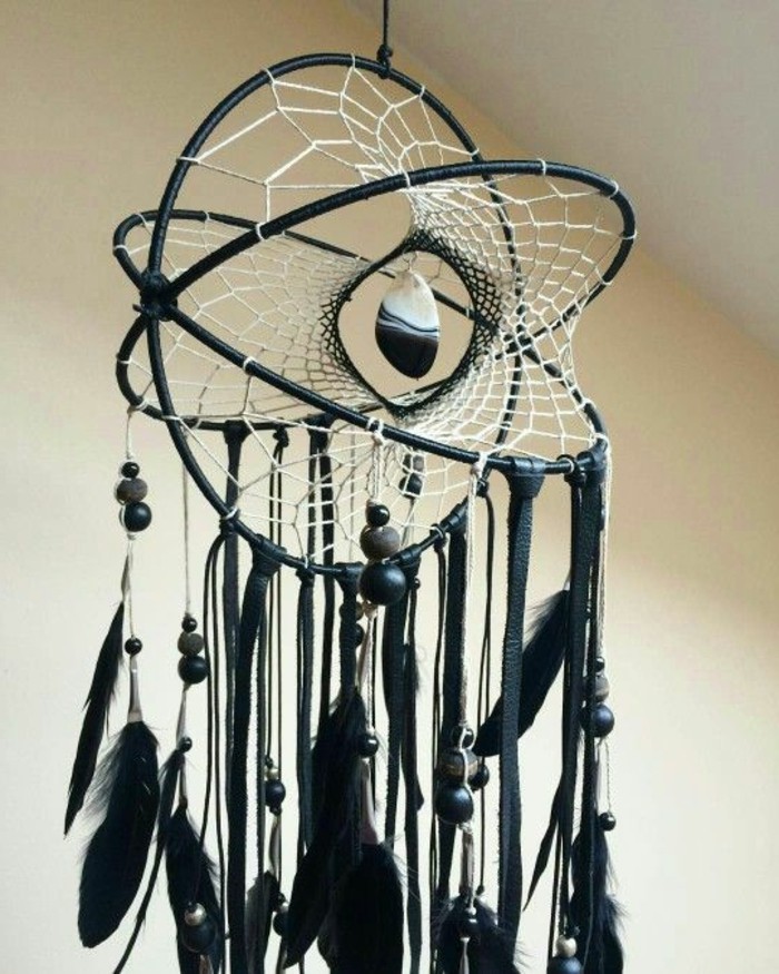 four dimensional dream catcher, in black with a white net, decorated with multiple black feathers, a black and white stone, and dark grey and black beads