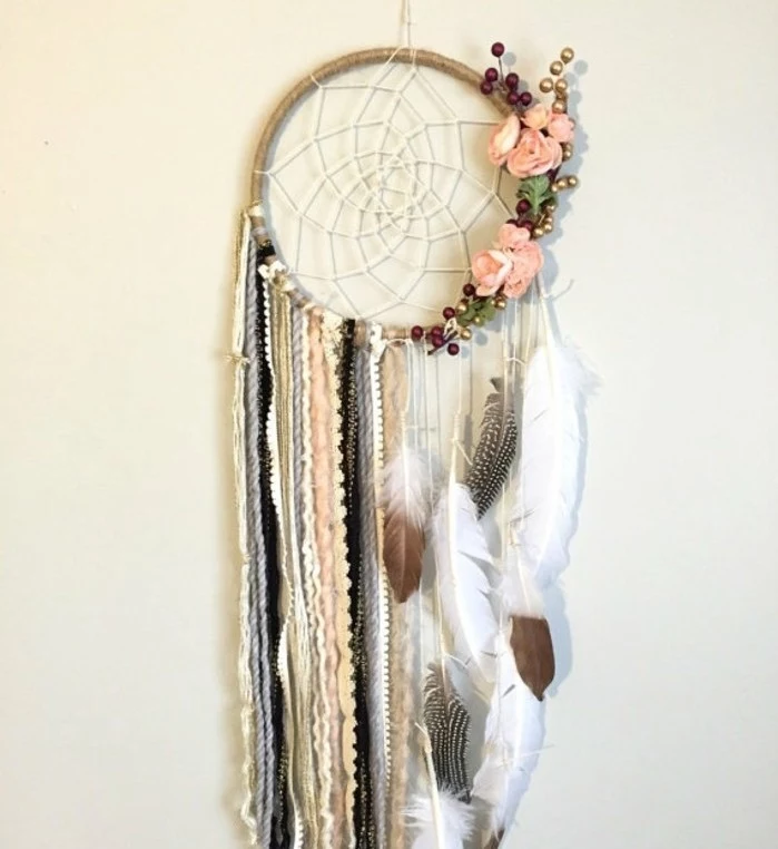 boho-style dreamcatcher, decorated with multiple crochet lace strips, feathers and flowers, how to make a dreamcatcher, hanging on a cream wall
