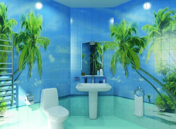 tiles in pale blue and turquoise, with images of a beach, with green palm trees, on the walls of a bathroom, containing a white ceramic toilet seat, and a matching sink