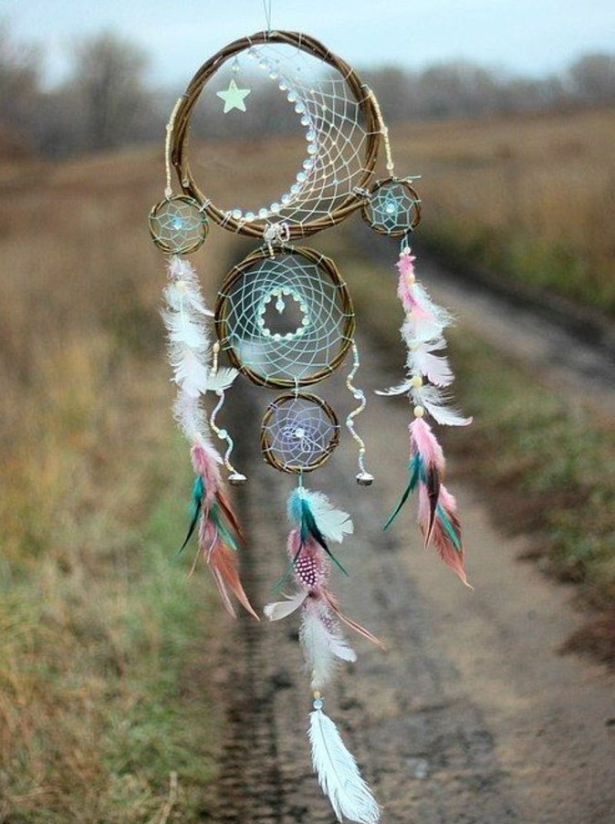 star ornament and lots of feathers, in pale white, pink and blue, decorating a handmade dreamcatcher, with three nets