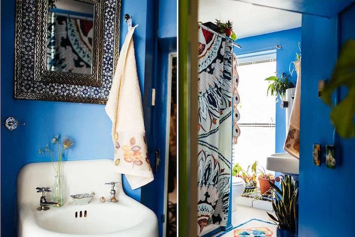 azure blue walls, and a vintage white sink, with rounded edges, in a room with a small mirror, in a detailed ornamental frame, small bathroom decoration ideas, multicolored shower curtain, and potted plants