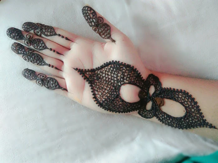 dense and dark henna hand tattoo, with details on the fingers, the lower part of the palm, and the wrist