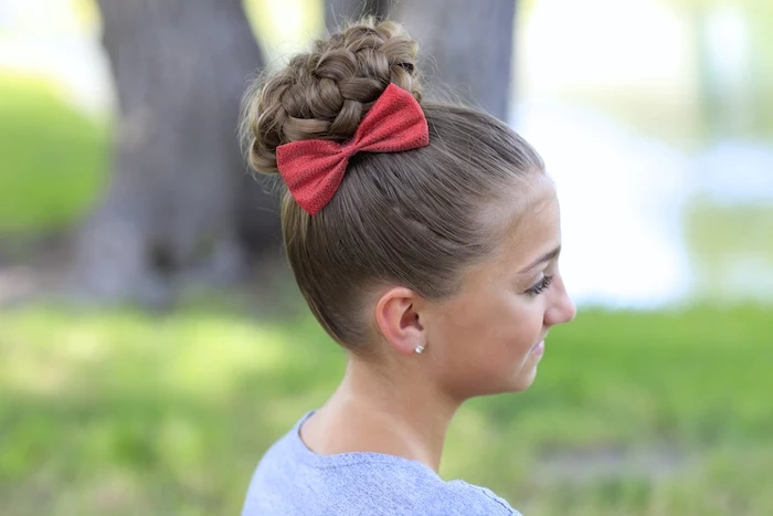 cute hairstyles, braided hair bun, on a brunette child's hair, decorated with a red bow