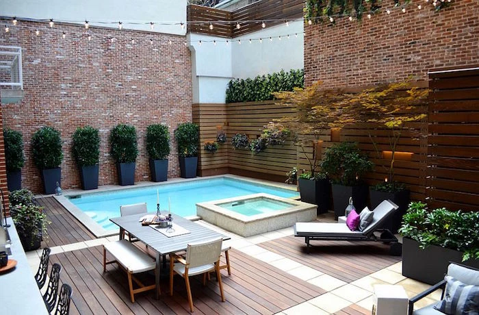 shrubs planted in pots, near two small pools, in a yard surrounded by brick walls, and containing a table with chairs and benches, cool backyards, sun bed with cushions