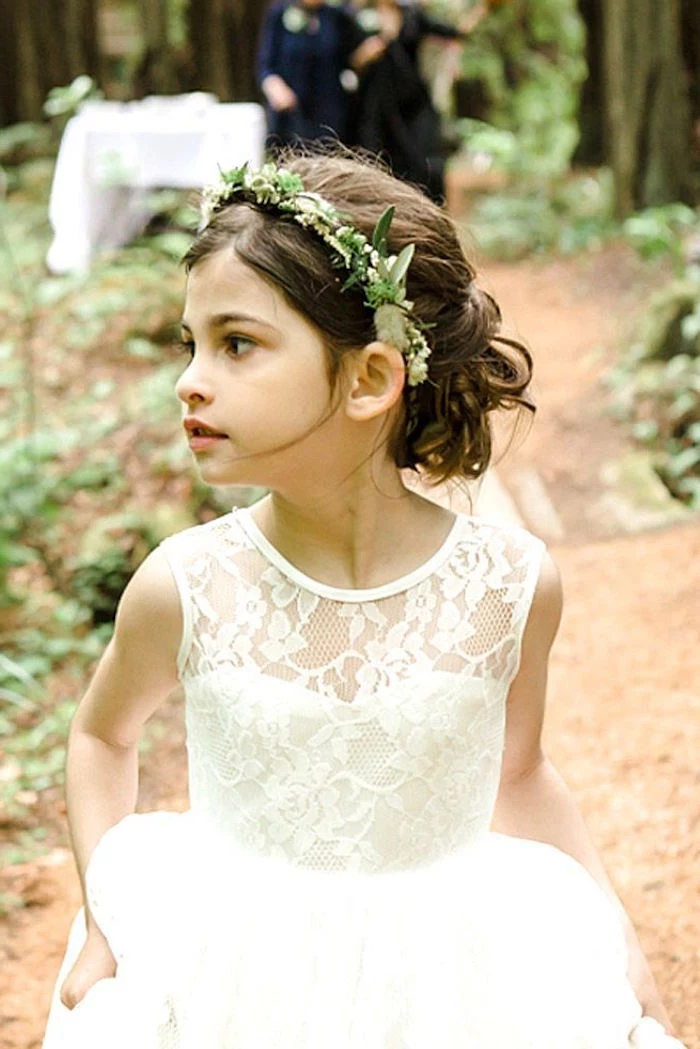 lace and tulle dress in white, worn by a small flower girl, with brunette hair, done in a curly half up-do, and decorated with a flower wreath