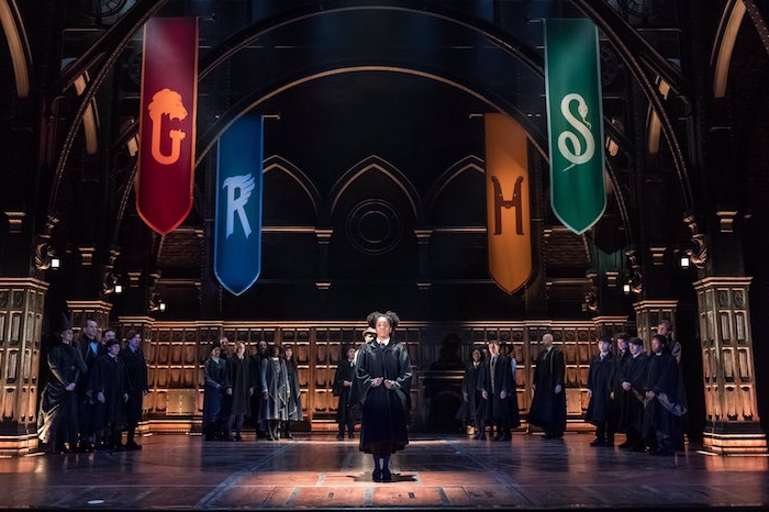 best set designers, children wearing black robes, standing on a stage, decorated with gothic elements, and colorful banners