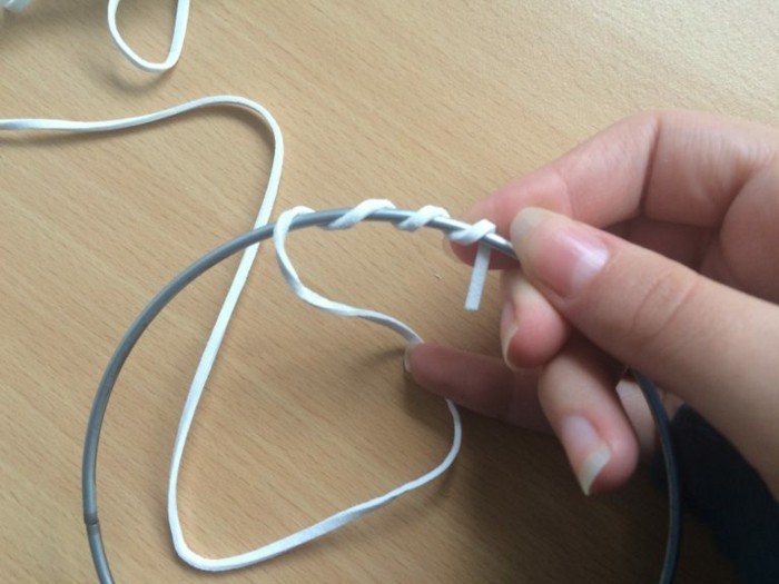 how to weave a dreamcatcher, hand holding a wire hoop, white leather rope, partially twisted around it