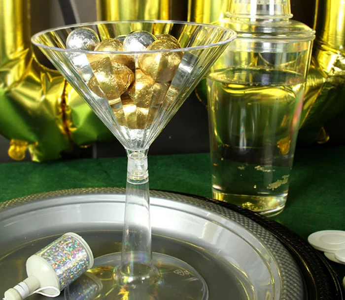 martini glass made from clear plastic, filled with round candies, in gold and silver wrappers, 60th birthday party ideas for men, james bond casino royale theme