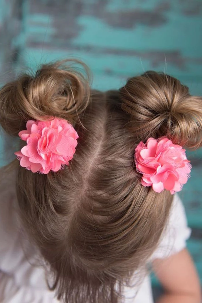 high-angle photo, showing a child's head, with chocolate brown hair, tied in two pigtails, hairstyles for little girls, coral pink flower-shaped hair ornaments