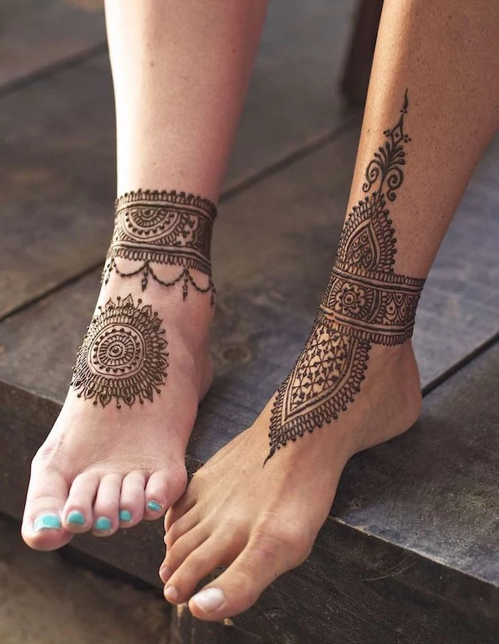 man's and woman's leg, lightly touching, henna meaning, hers with mandala and ankle bracelet-like henna tattoos, his with an elaborate mehndi design