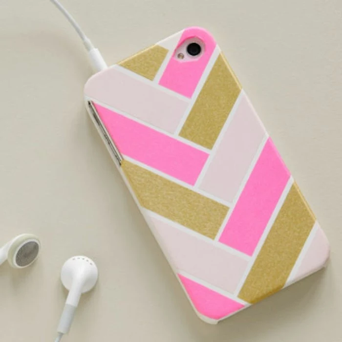 cute gift ideas, mobile phone case in white, decorated with hot pink, shimmering gold and pale pink strips, white earplugs attached to it