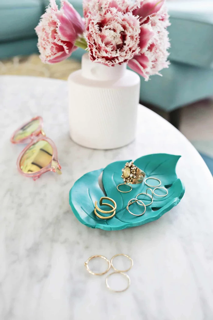 white vase with flowers, leaf shaped turquoise clay jewelry holder, diy gift ideas, placed on marble surface, gold rings inside