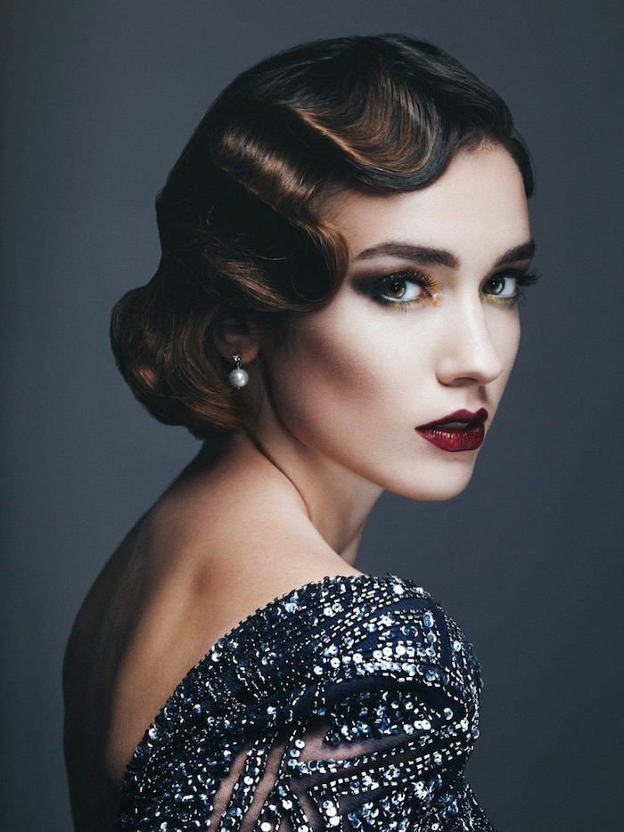 wavy bobbed brunette hair, worn by a woman with 1920s make up, dark eyeshadow and red lipstick, backless dress covered with silver sequins