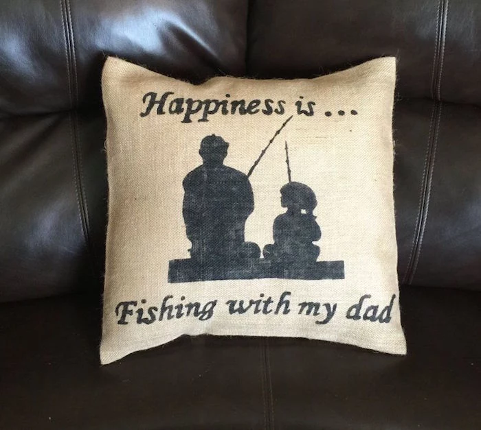 silhouettes of a man and a little girl, both holding fishing rods, decorating a pale beige cushion, with the inscription, happiness is...fishing with my dad