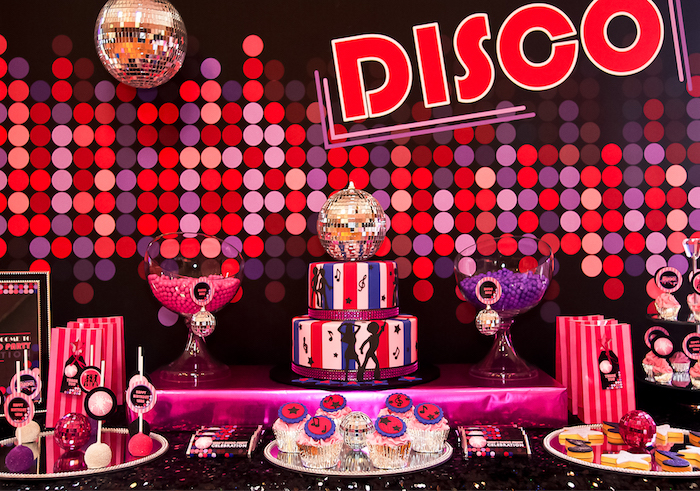 purple red and pink polka dots, on the wall near a party table, with a red white and blue striped cake, various different kinds of sweets, and two disco balls, 60th birthday party ideas, retro disco theme