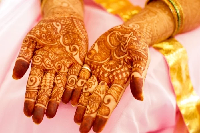 bridal mehndi in reddish brown, covering the palms of two hands, henna tattoo with many details, drums and flourishes
