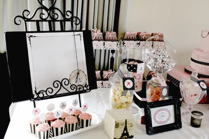 french-themed birthday party, in black and pale pink, table with candies and cupcakes, decorated with an eiffel tower ornament, and other items