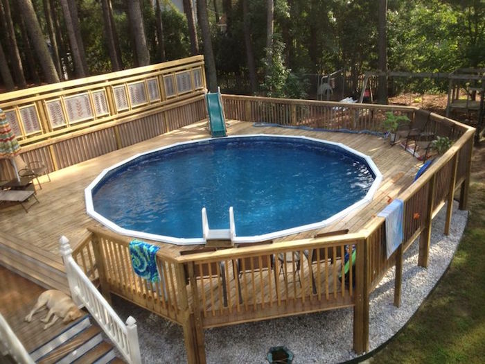 swing set and lots of tall trees, near a patio pool, with a tiny slide, small above ground pools, sleeping dog on the pool stairs