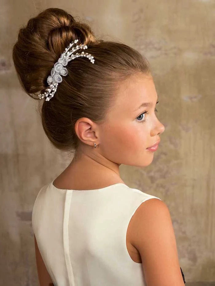 silver hair ornament, with diamante details, decorating the hair bun, of a brunette young girl, wearing a smart white dress