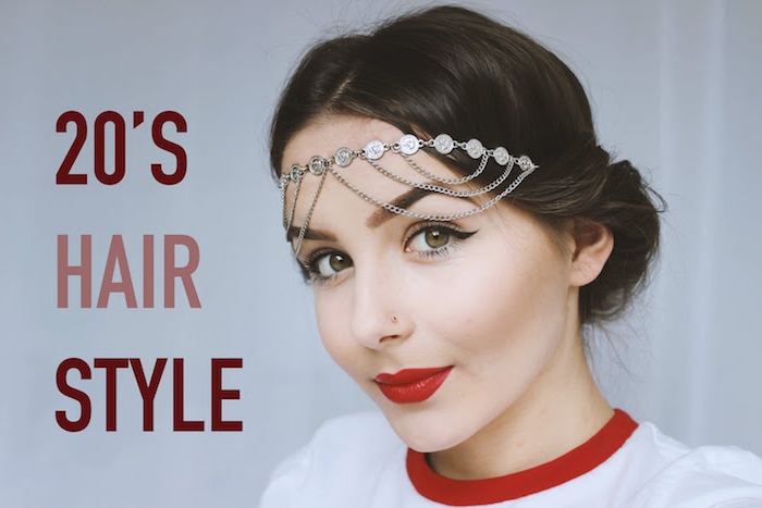 nose stud and eyeliner, bright red lipstick and a silver flapper-style headband, worn by a young woman, in a white and red top