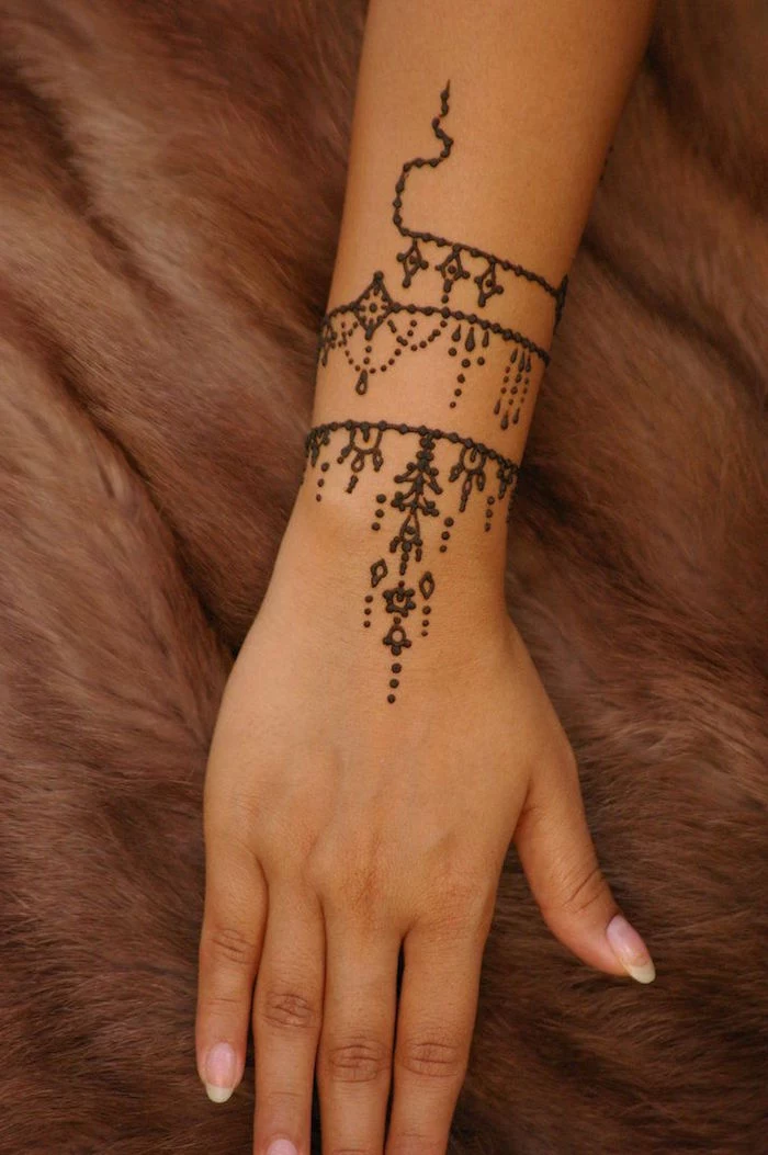 blanket made from brown faux fur, under an arm, decorated with a small henna tattoo, in a winding pattern
