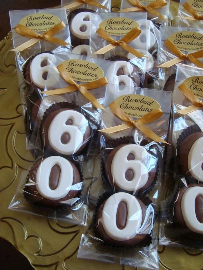 yellow ribbons decorating several clear packages, containing two milk chocolate cupcakes each, decorated with the numbers 6 and 0, made from white chocolate 