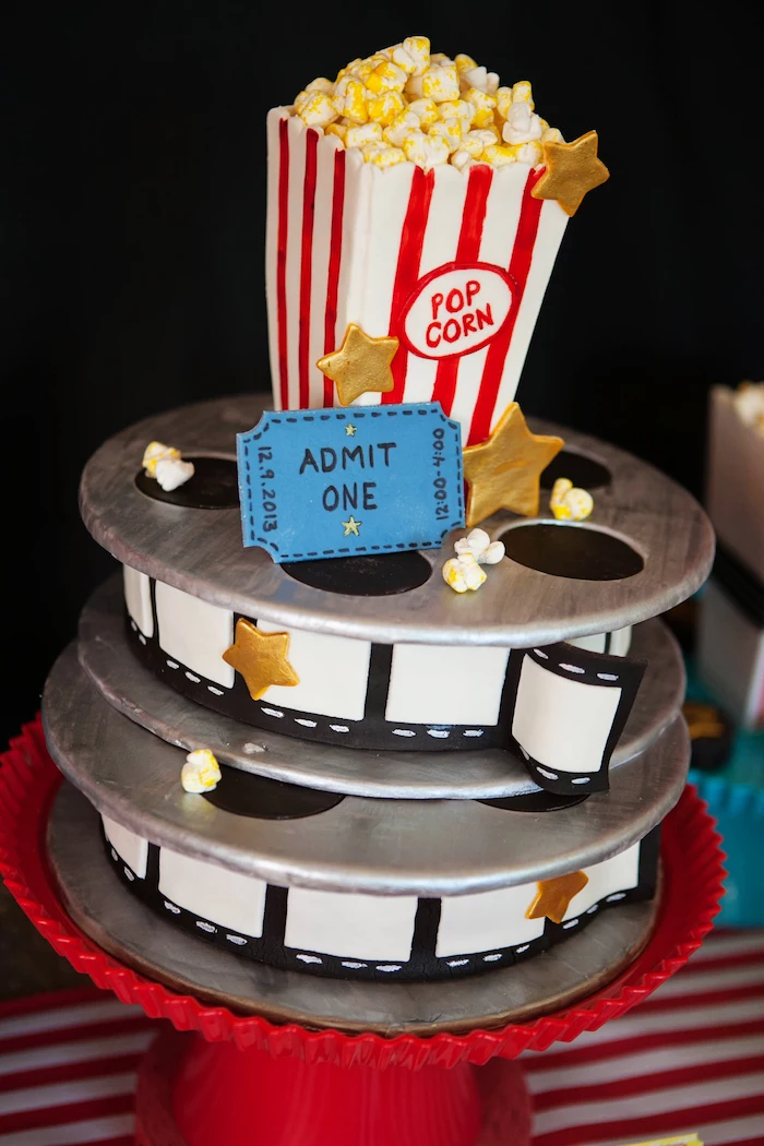 60th birthday decorations, colorful fondant-covered cake, shaped like film reels, and a vintage box of popcorn, decorated with gold stars, and a blue admission ticket