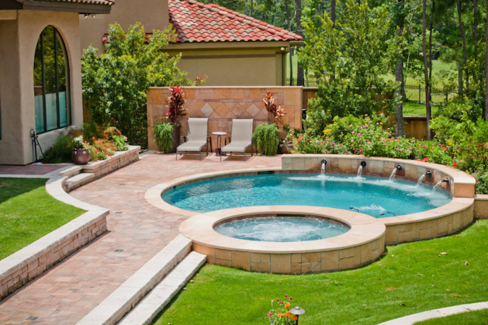 set of two pools, with five faucets, pouring water into the bigger one, green grass and a tiled path, backyards with pools, lots of green trees and a house