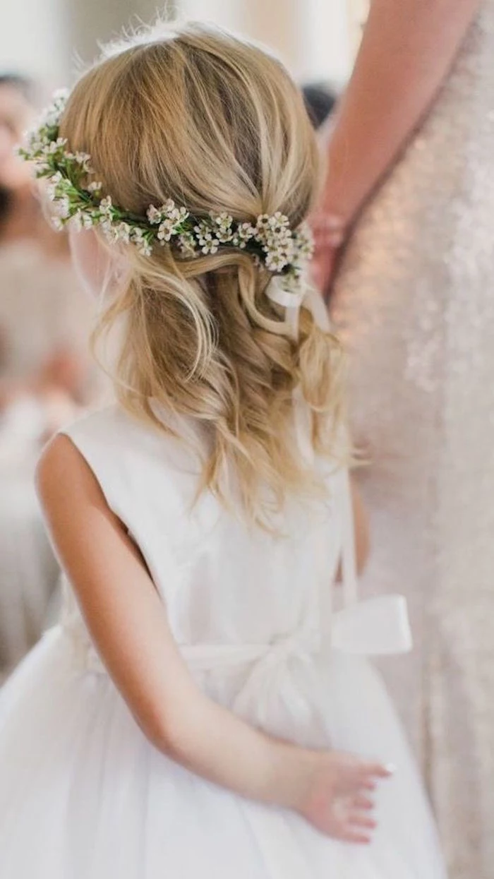 straw blonde shoulder-length hair, with loose curls, worn by a young child, in a white flower-girl dress, girl haircuts, flower wreath wth small white blossoms