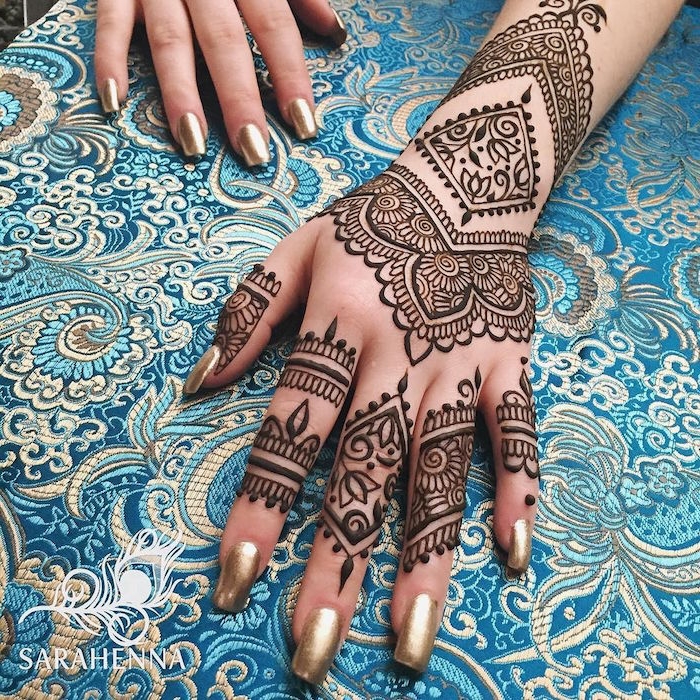 metallic gold nail polish, on a hand decorated with mehndi, cute henna designs, flowers and geometric figures