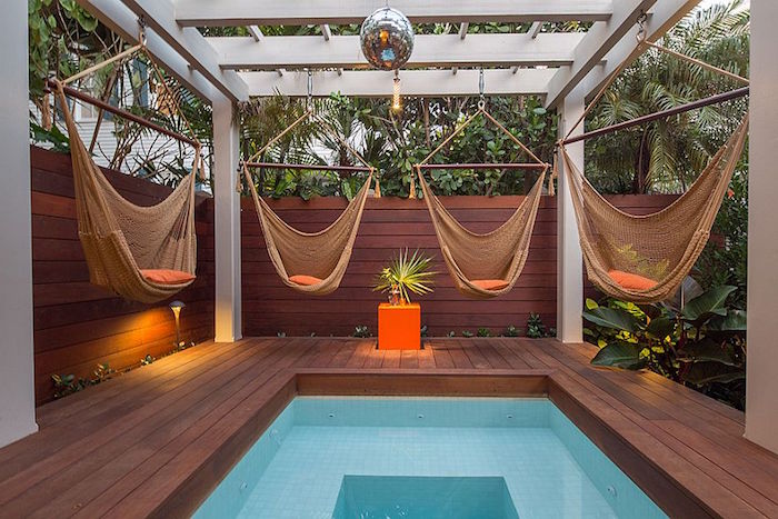 disco ball and four hammock swings, hanging from a white wooden structure, built over a small rectangular pool