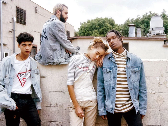 group of young people, dressed in 90s getup, oversized denim jackets, overalls and a turtleneck