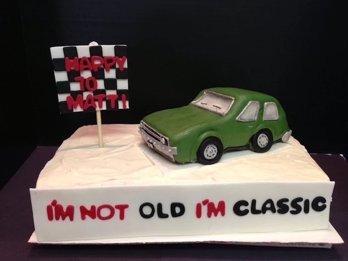i'm not old i'm classic, written in red and black icing, on the side of a white rectangular cake, topped with a green vintage car, 60th birthday party ideas for men