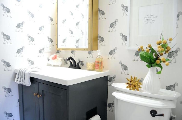 ostrich patterned wallpaper, in white and grey, small bathroom décor, black cupboard with an inbuilt white sink, white toilet and various decorations