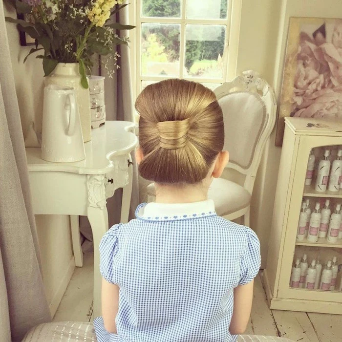 checkered blue and white dress, with a white embroidered collar, worn by a child, with honey blonde hair, braided into a large side bow, girl haircuts, seen from the back