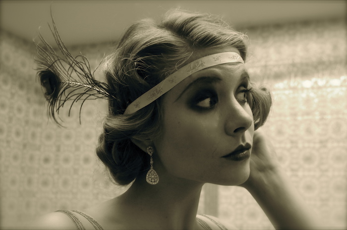 faux vintage photo, with a sepia tint, showing a close up of a woman's head, hair and make up styled like a 1920s flapper