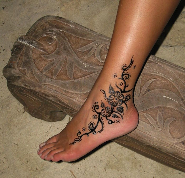 cute henna designs, little flowers and flourishes, leaves and dots, painted on a woman's foot, with black henna