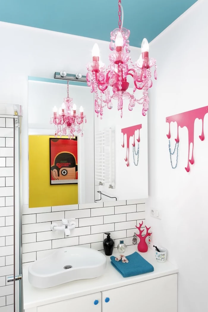 pop art inspired room, with a teal blue ceiling, and a hot pink chandelier, white walls partially decorated with white subway tiles, and decorations in hot pink and blue, small bathroom decorating ideas, a clockwork orange poster
