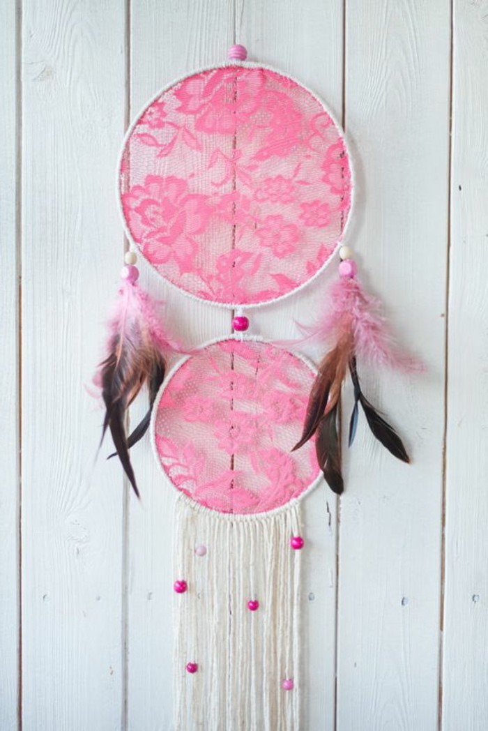 neon pink lace, decorating a white dream catcher, with brown feathers, and white tassels, dreamcatcher designs, white wooden planks in the background