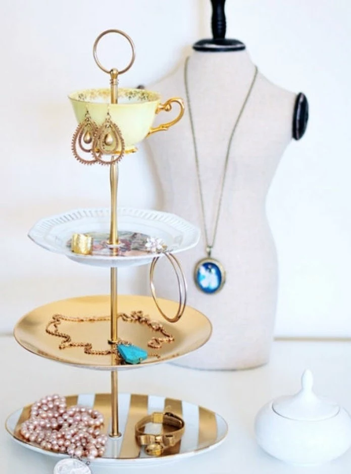 plates and a teacup, spray painted in gold, white and yellow, and attached to a gold pole, to form a jewelry organizer, cute birthday ideas, bracelets and rings, necklaces and earrings inside