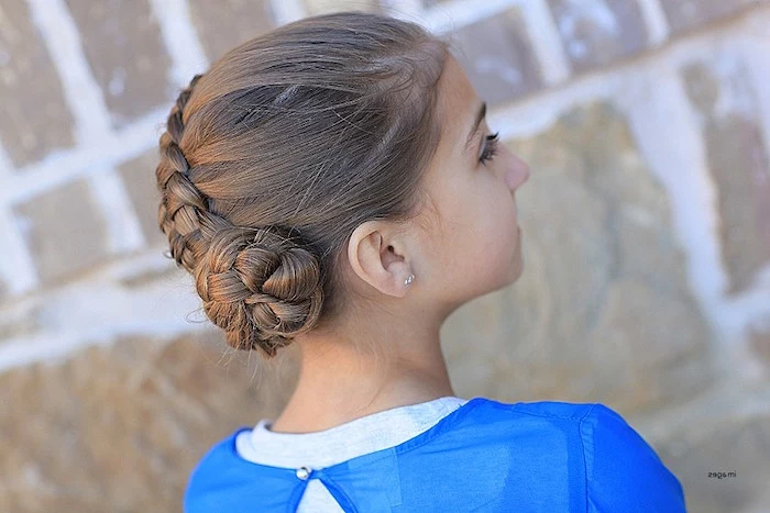 blue layered top, worn by a young brunette girl, with a braid, ending in a swirl-like detail, kids hairstyles, seen from the side