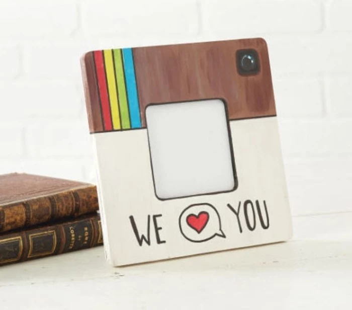 square frame, painted to look like the instagram logo, with the words we and you, divided by a speech bubble, containing a heart symbol