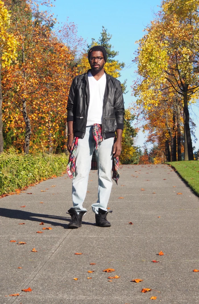 pilot's leather jacket in black, worn over a white v-neck sweater, and pale jeans, 90s aesthetic, worn by a black man, with a flannel shirt tied round the waist