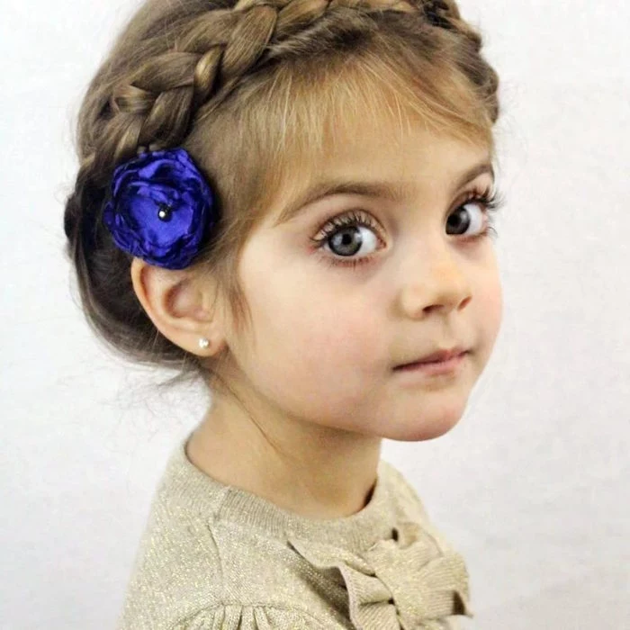 electric violet flower ornament, behind the ear of a small child, with big blue eyes, and light brunette hair, woven into a crown braid