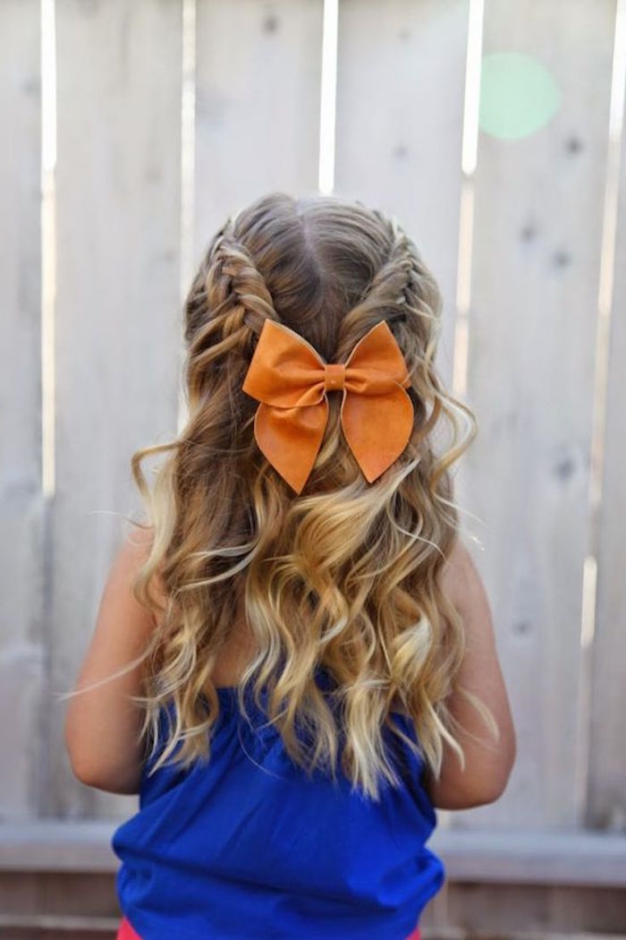 orange hair bow, decorating two joining braids, on the back of a girl's head, long curled dark blonde hair, with natural highlights