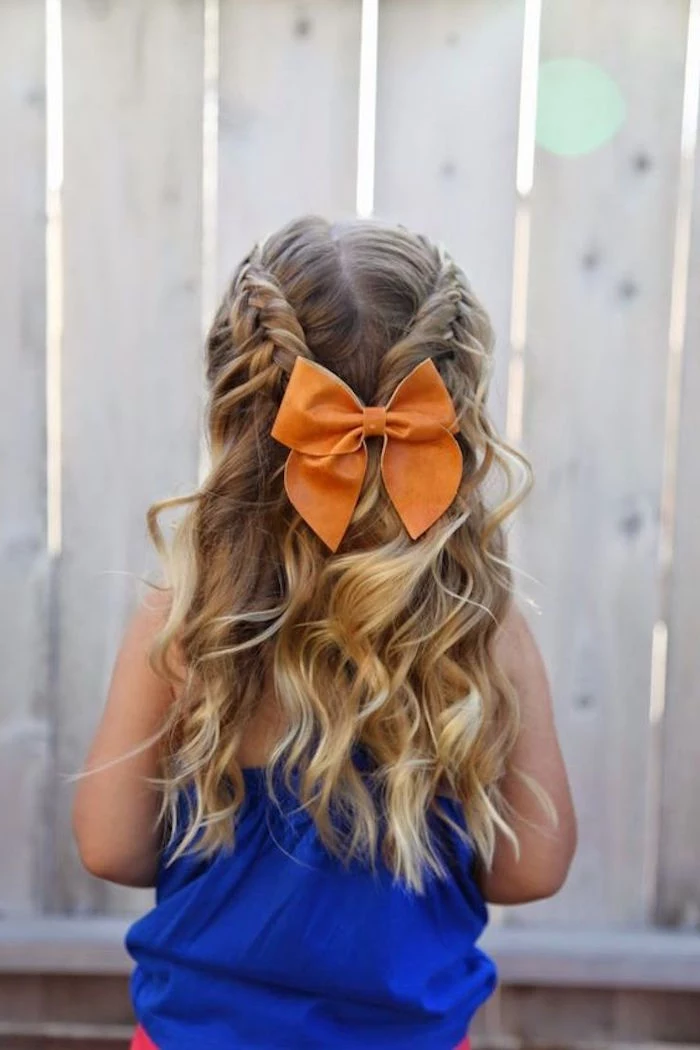 orange hair bow, decorating two joining braids, on the back of a girl's head, long curled dark blonde hair, with natural highlights