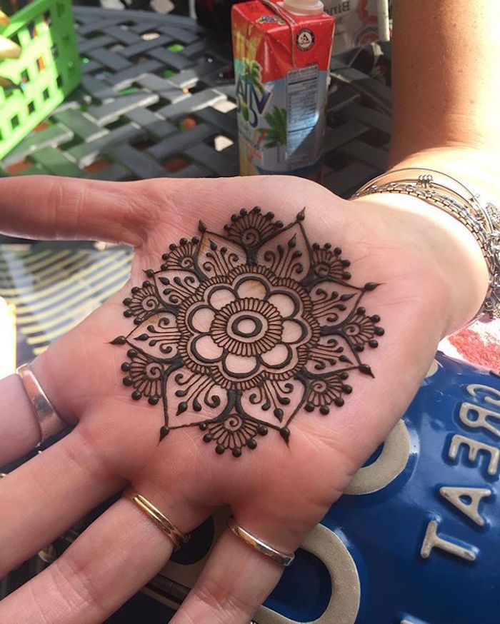 henna hand tattoo designs, perfectly symmetrical flower mandala, painted with brown henna, on the palm of a hand