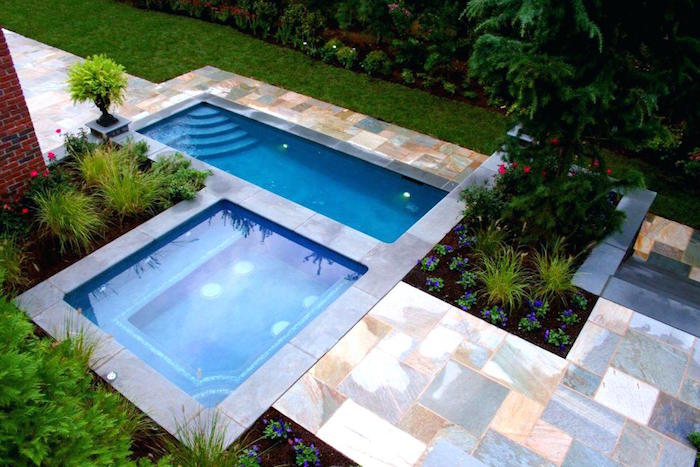 horizontal and vertical small pools, in a garden with green grass, marble-like tiles, and various shrubs